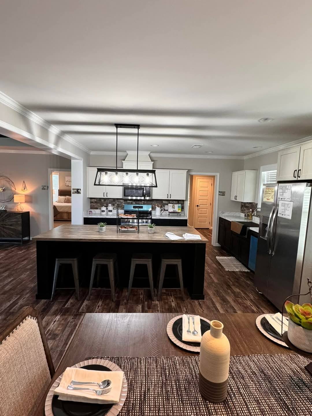 Modern kitchen with a large island and four stools. Stainless steel appliances and white cabinetry enhance the sleek, inviting atmosphere.
