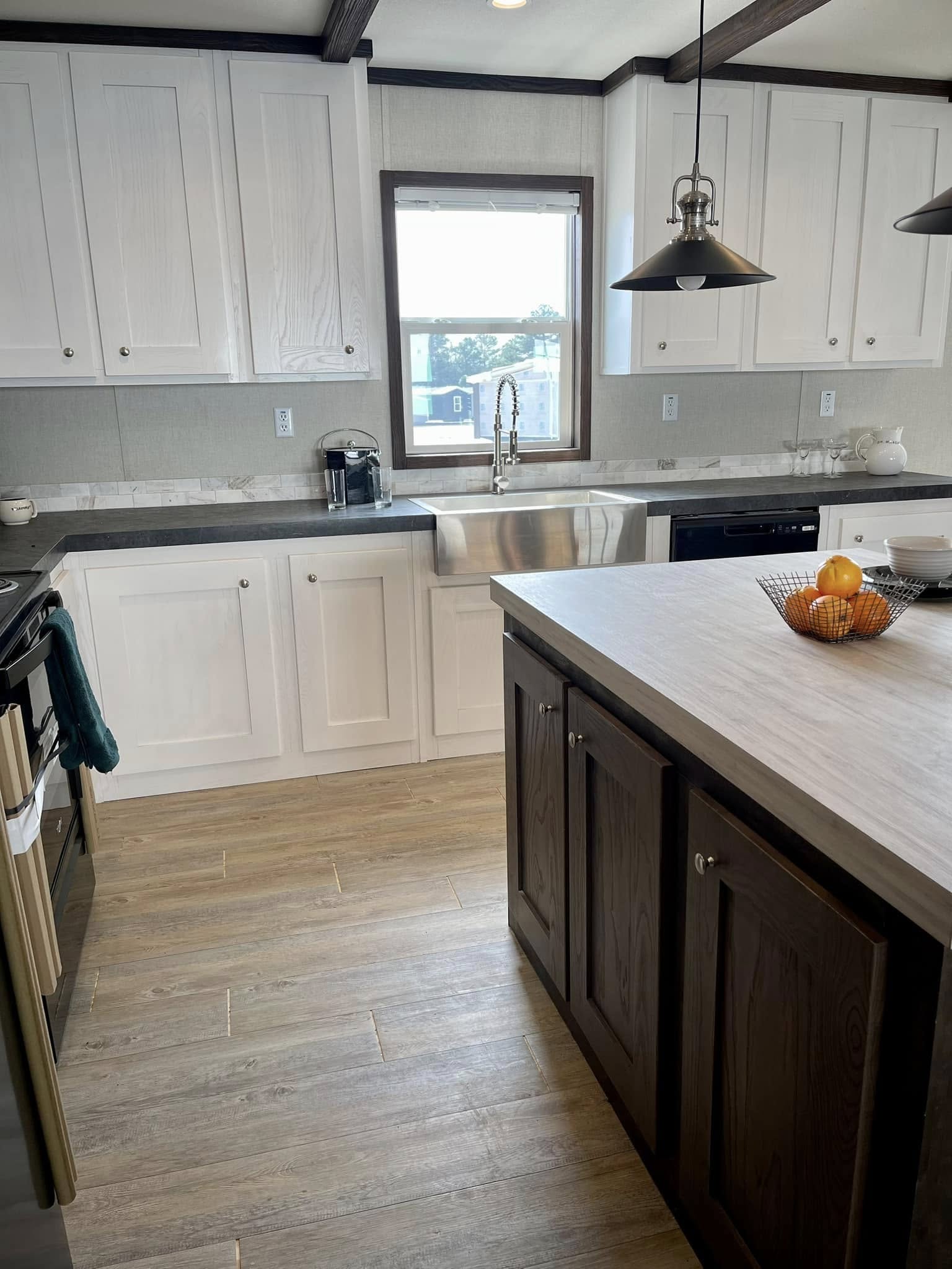 Bright kitchen with white cabinets, stainless steel farmhouse sink, and wooden island. Cozy, modern feel with pendant lights and light wood flooring.