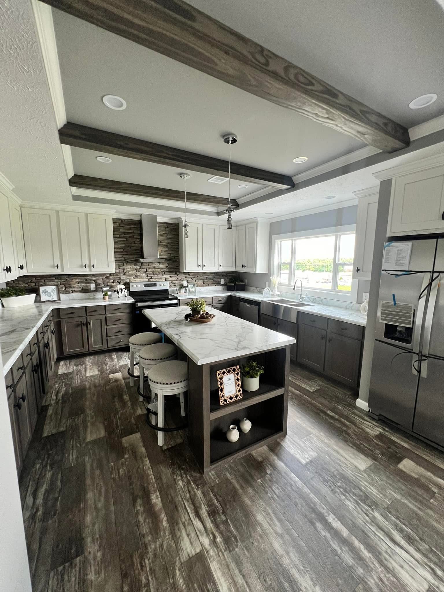 Modern kitchen with marble countertops, dark wood cabinets, and a central island with stools. Brick backsplash and large window create a bright, inviting space.