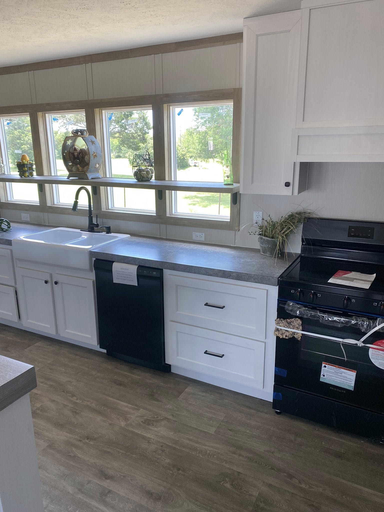 Modern kitchen with a large island featuring three wooden stools. It's decorated with baskets and bowls, and has white cabinets and large windows.