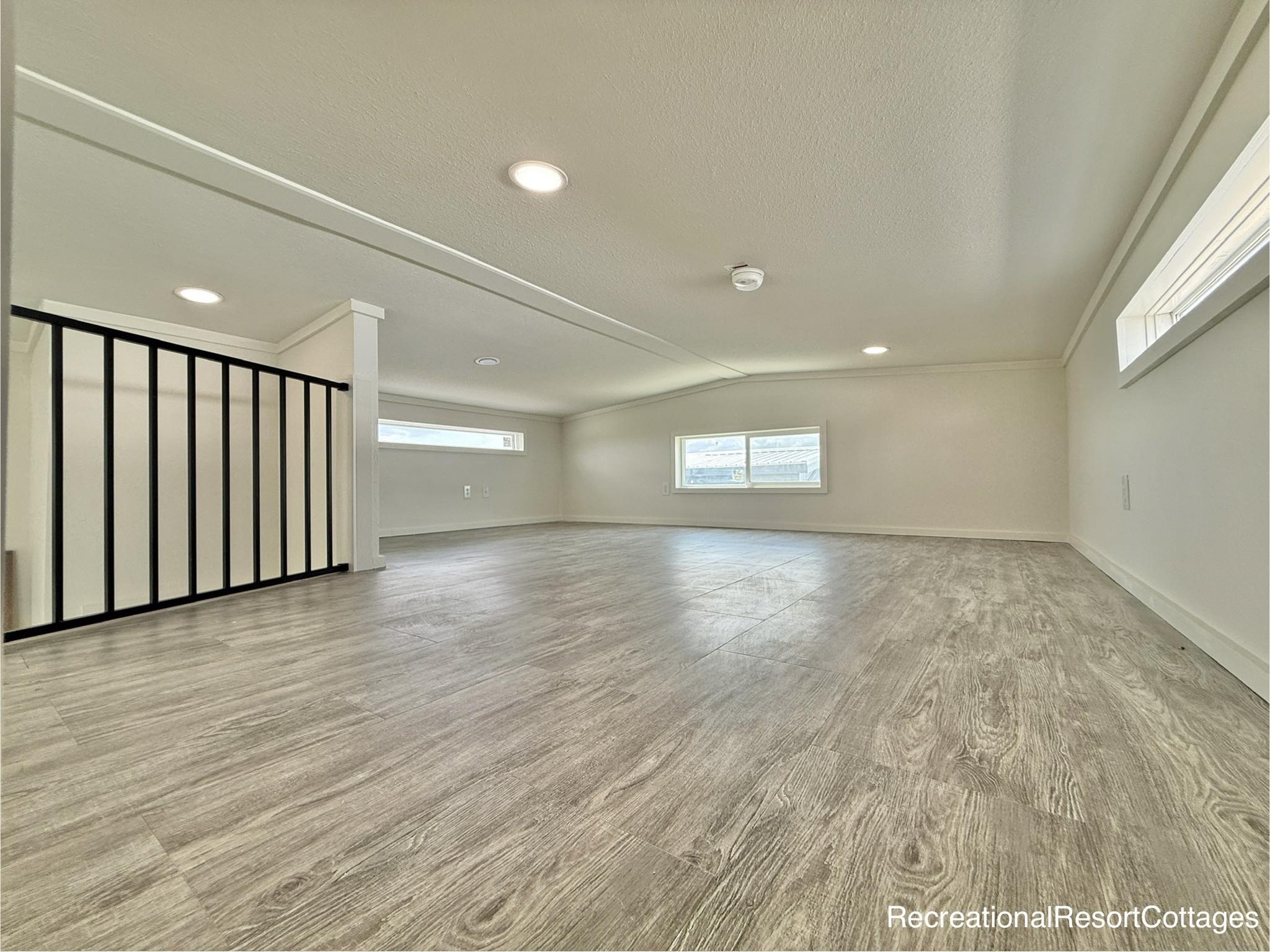 Spacious, modern loft with a light wood floor, recessed lighting, and horizontal windows. Bright, airy ambiance with minimalistic design.