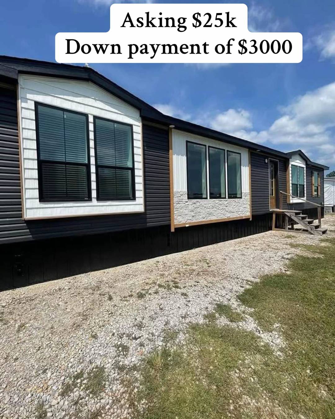 Dark-colored manufactured home under a partly cloudy sky, with a sign indicating the price: $25k and a $3000 down payment. A gravel pathway lies in front.
