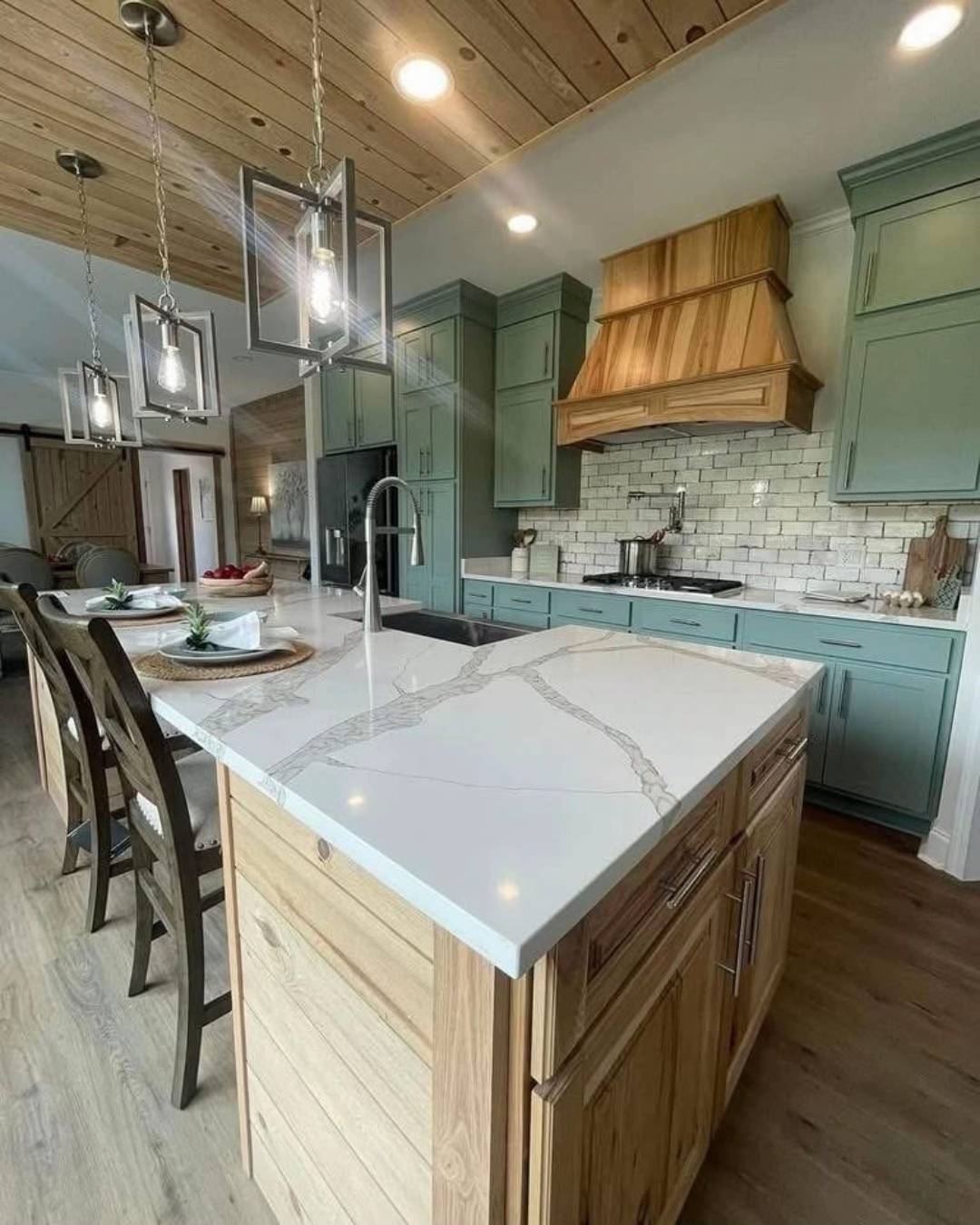 Modern kitchen with light wood ceiling and flooring, mint green cabinets, white quartz countertops, and pendant lights. Warm, inviting atmosphere.