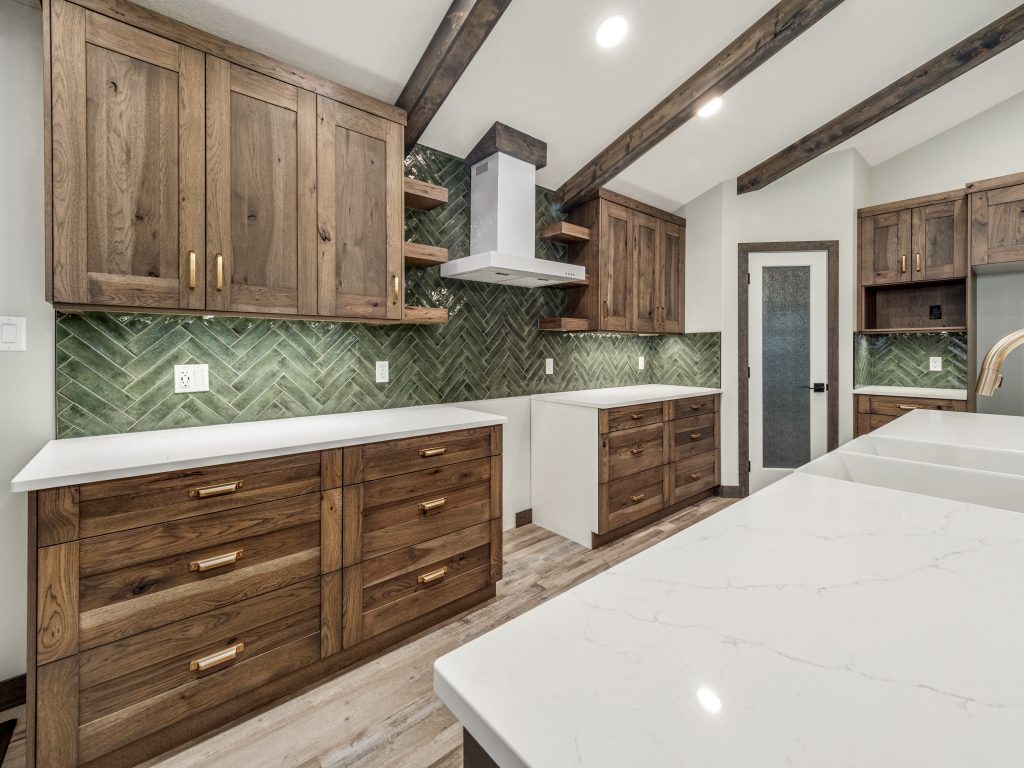 Modern kitchen featuring wooden cabinets, green herringbone tile backsplash, white quartz countertops, exposed wooden beams, and rustic elegance.