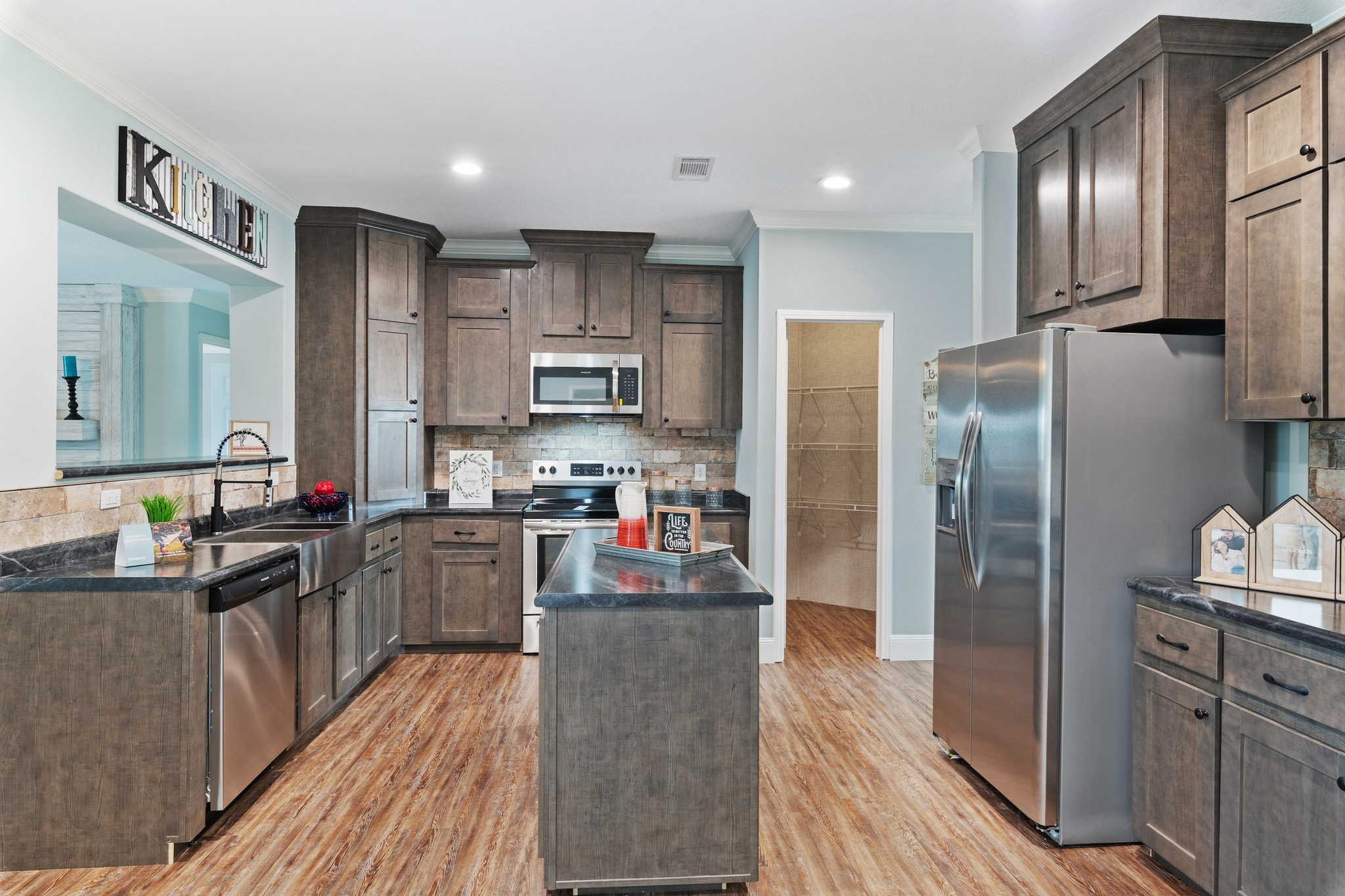 Spacious kitchen with wooden cabinets, stainless steel appliances, a central island, and wood flooring. Bright and inviting atmosphere.