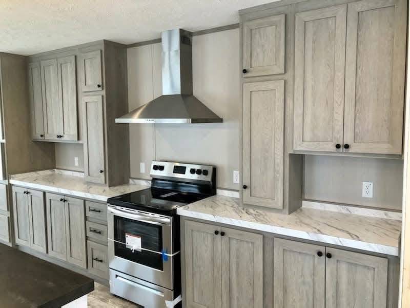 Modern kitchen with light wood cabinets, marble countertops, and a stainless steel stove with a sleek range hood. Neutral tones create a clean, elegant look.