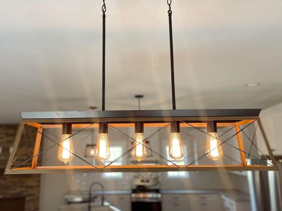 Modern industrial kitchen light fixture with five exposed Edison bulbs in a rectangular metal frame. Warm glow creates a cozy, stylish ambiance.
