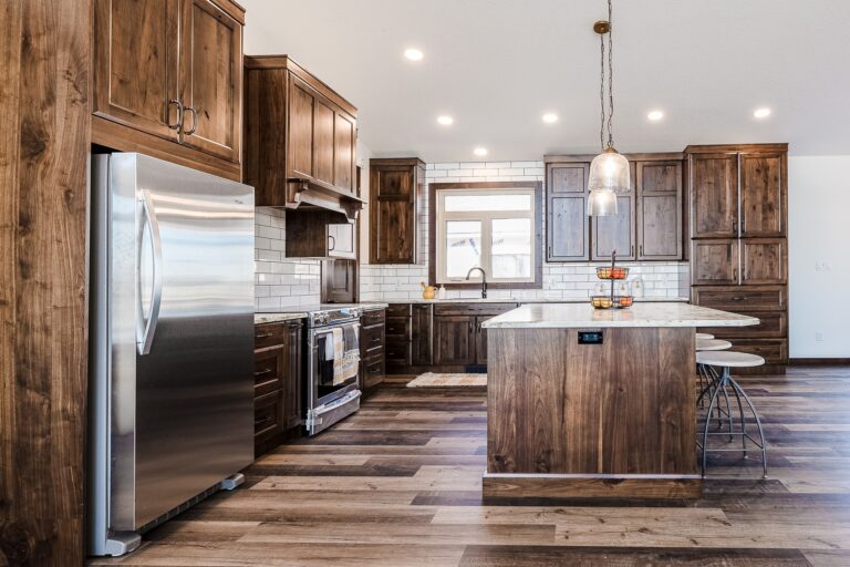 Spacious kitchen with rustic wood cabinetry, stainless steel appliances, and a central island. Pendant light adds warmth to the modern decor.