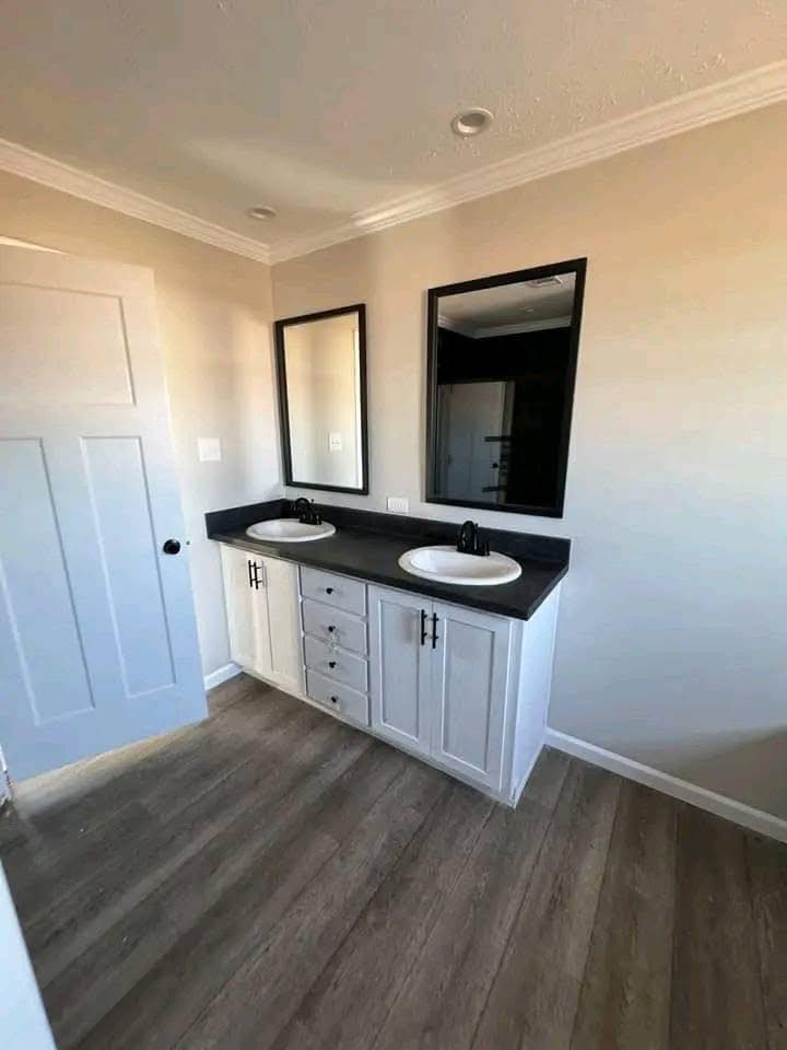 Modern bathroom showcasing a double vanity with white cabinets, dark countertop, and two rectangular mirrors. The clean design exudes a minimalist feel.
