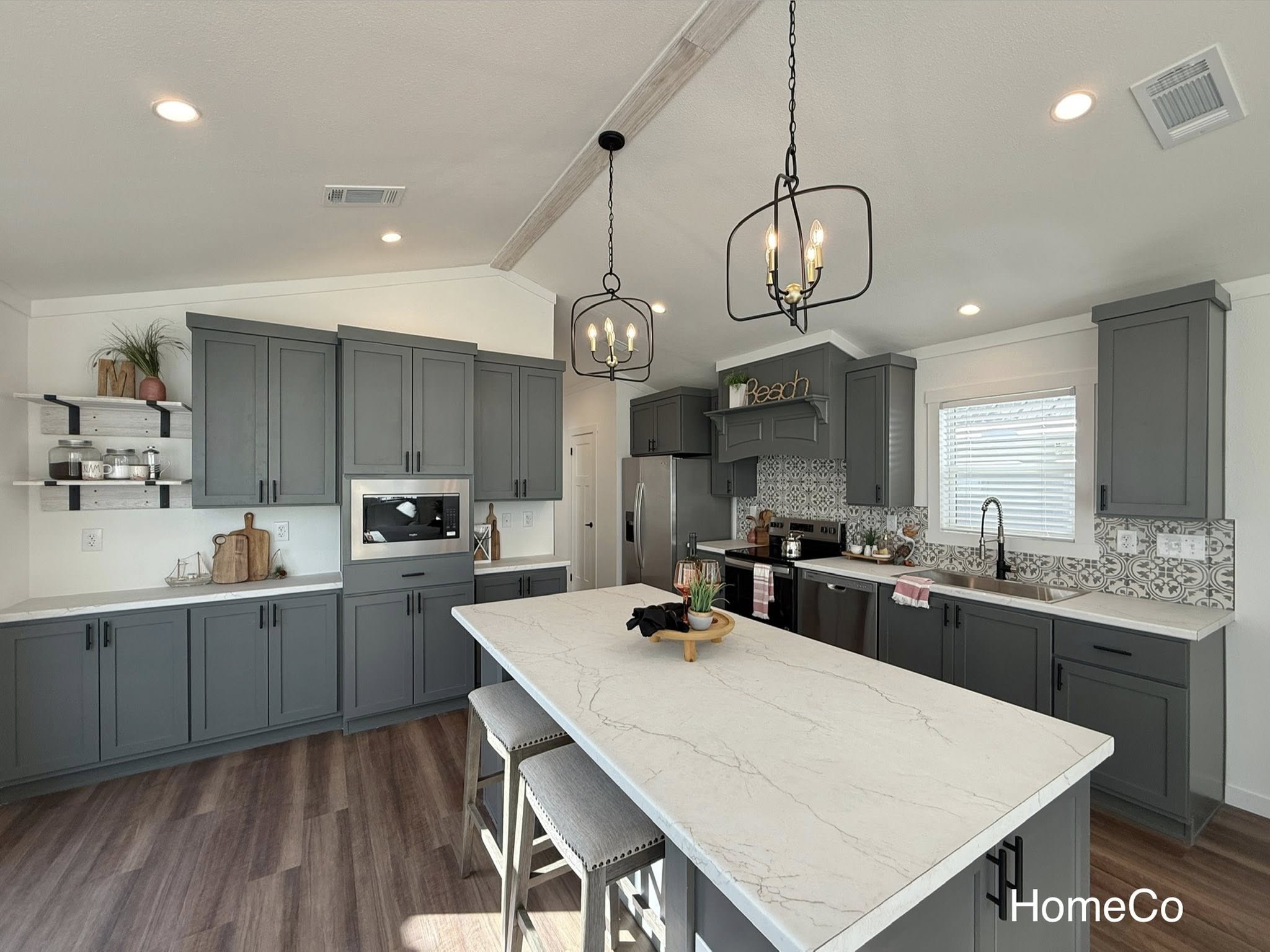 Modern kitchen with gray cabinets, a marble island, pendant lights, and a patterned backsplash. Bright, spacious, and contemporary ambiance.