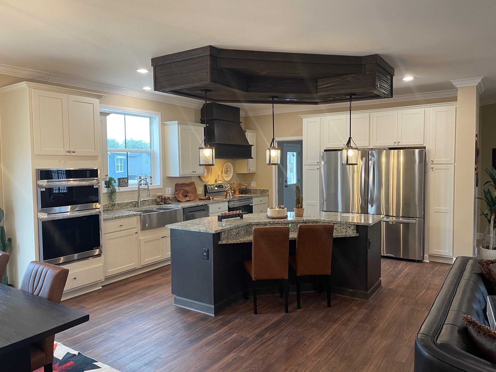 Modern kitchen with white cabinets and stainless steel appliances. Central island has granite countertop and pendant lights, creating a warm atmosphere.
