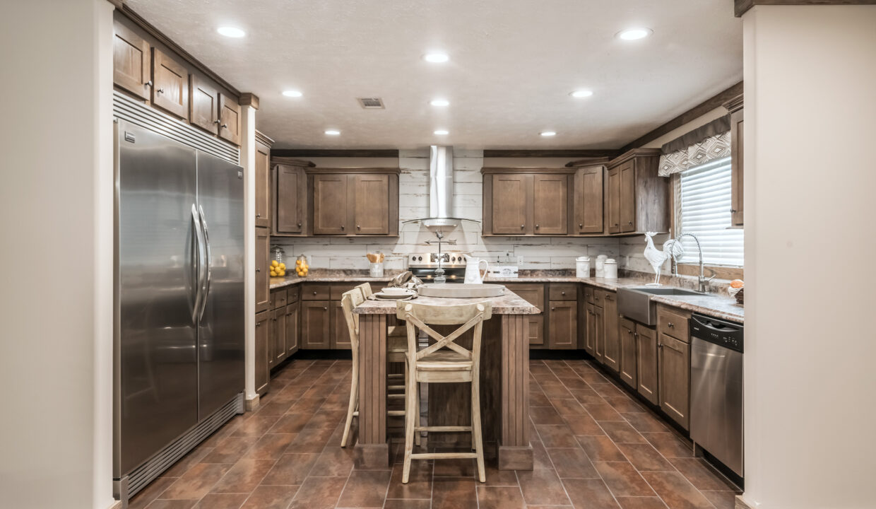 Spacious kitchen with wooden cabinets, a central island with two chairs, stainless steel appliances, and warm lighting. Cozy and inviting atmosphere.