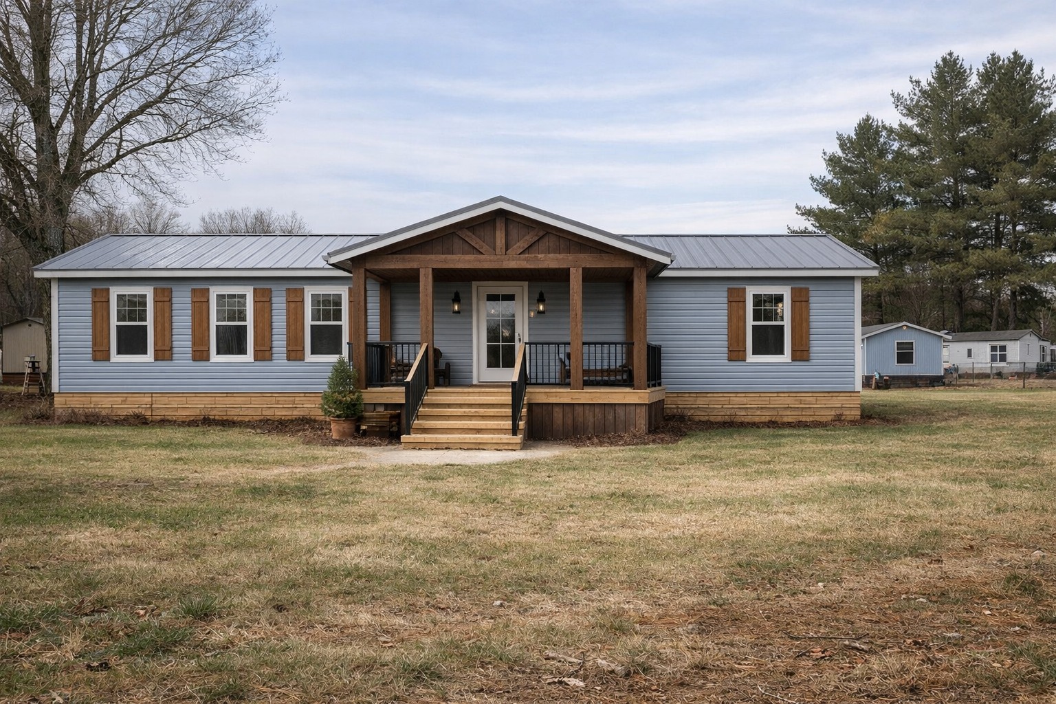 A blue ranch-style house with wooden shutters and porch railing, set against a cloudy sky. Surrounding the house is a grassy lawn and bare trees, creating a calm suburban atmosphere.