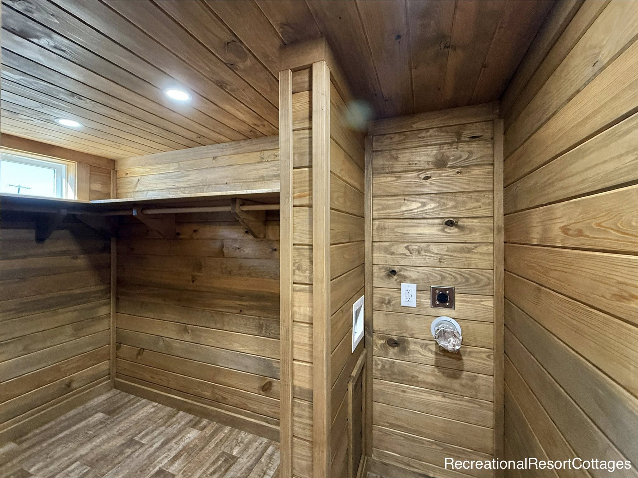 Warmly lit wooden interior with paneled walls and ceiling, recessed lights, and electrical outlets. Cozy and rustic atmosphere, suggesting a cabin feel.