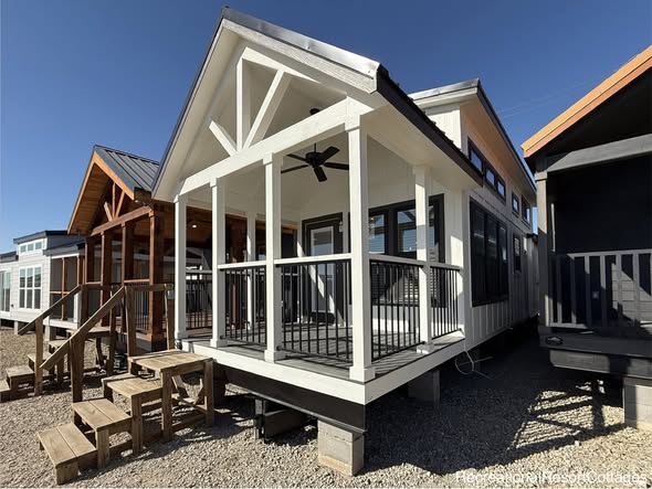 A row of charming tiny houses with wooden porches and gabled roofs under a clear blue sky. The scene conveys a warm, inviting atmosphere.