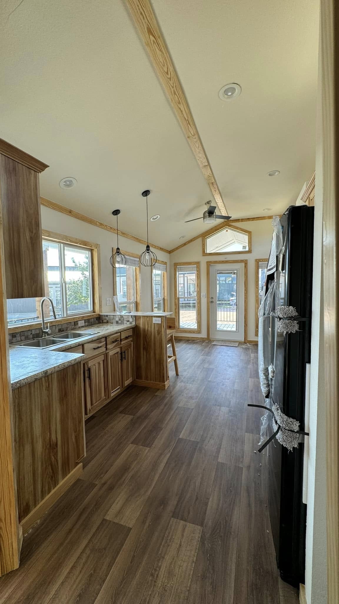 A spacious, modern kitchen with light wood cabinets, marble countertops, and pendant lights. A bright entrance and large windows enhance the airy feel.