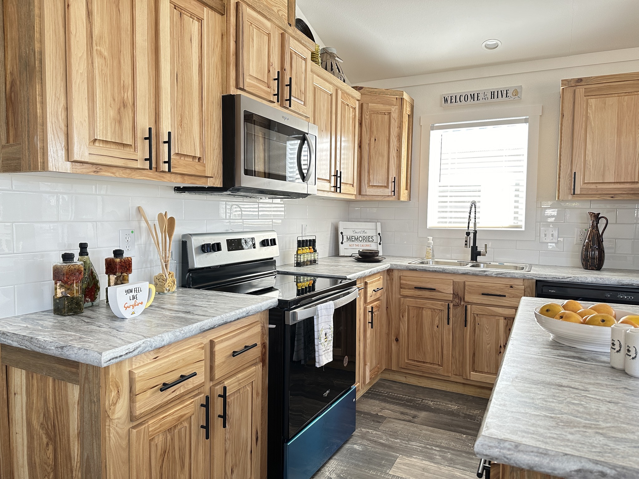Warm kitchen with wooden cabinets, granite countertops, and stainless steel appliances. A bowl of lemons adds a touch of freshness. Cozy ambiance.