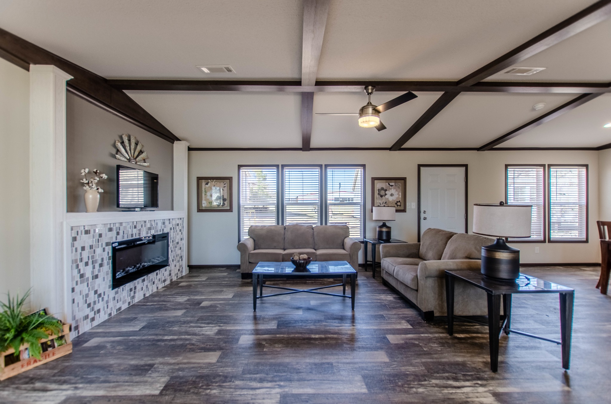 Spacious room with hardwood floors, a modern chandelier, and large sliding glass door leading outside. Built-in shelving and white cabinets under warm lighting.