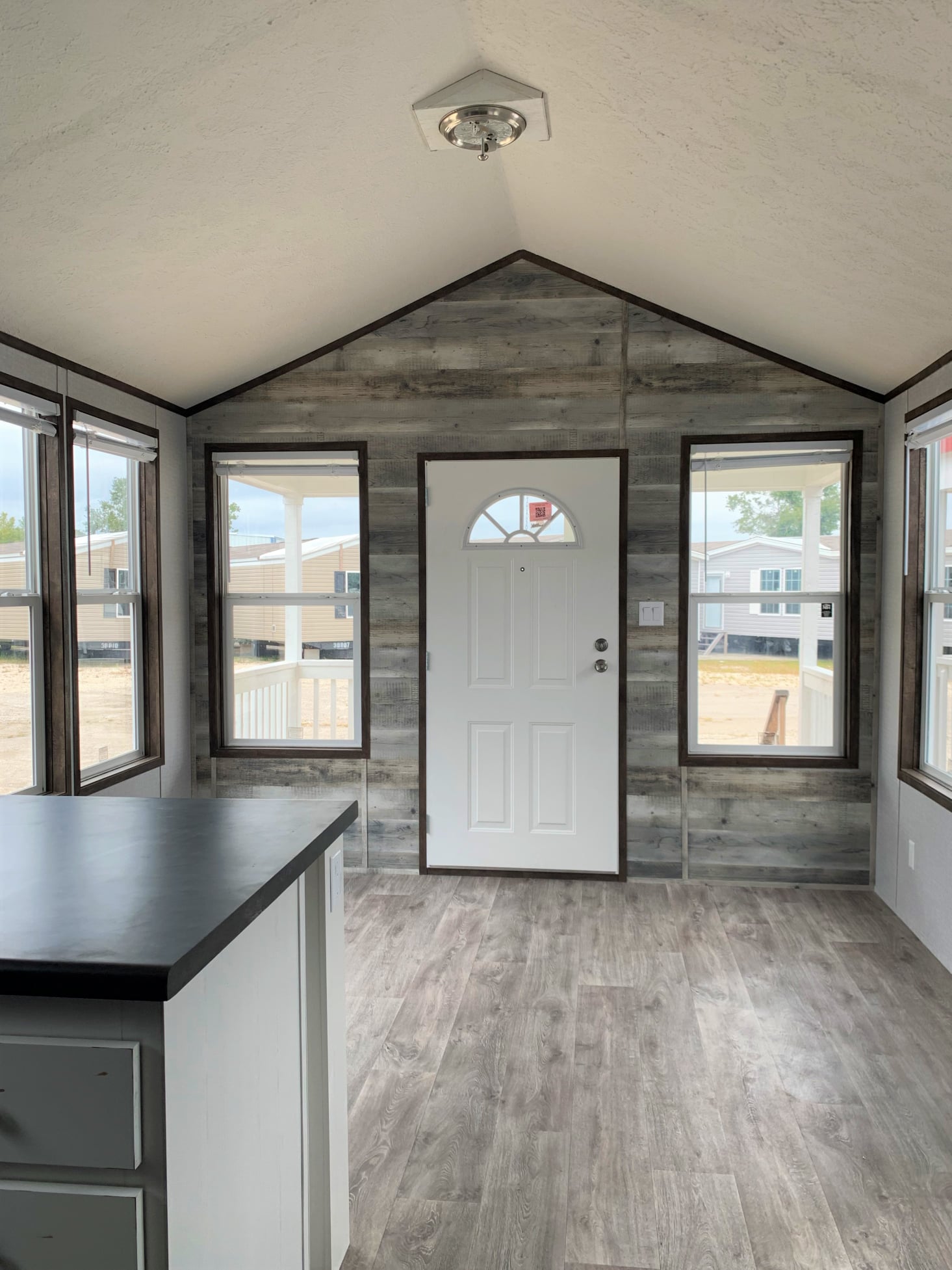 Small, bright room with wood-look flooring and rustic wooden walls. The arched door has large windows on either side, creating an airy feel.