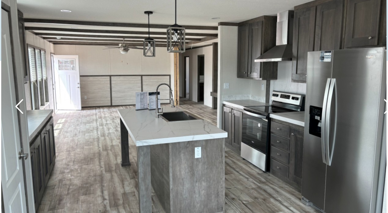 Modern kitchen with gray cabinets, stainless steel appliances, and a central island with a marble countertop. Bright, airy space with hardwood floors.