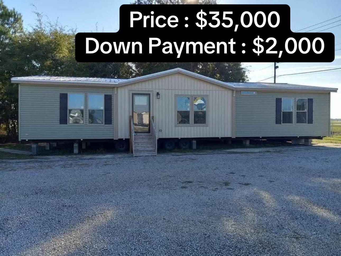 A beige mobile home with dark shutters is placed on a gravel lot with trees in the background. Text reads "Price: $35,000, Down Payment: $2,000."