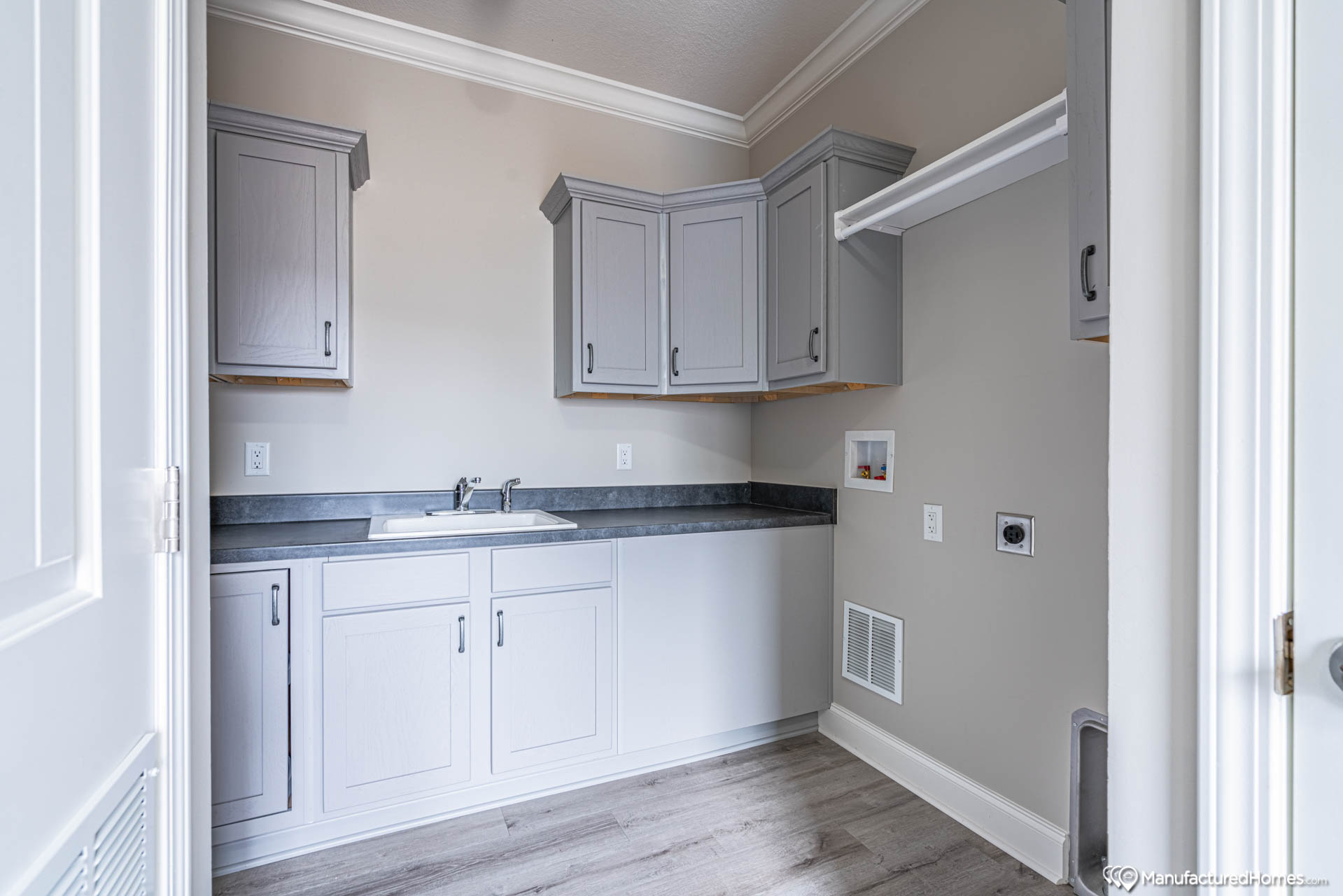 Minimalistic laundry room with light gray cabinets, a sleek countertop, and a utility sink. Soft lighting and neutral tones create a clean, organized feel.