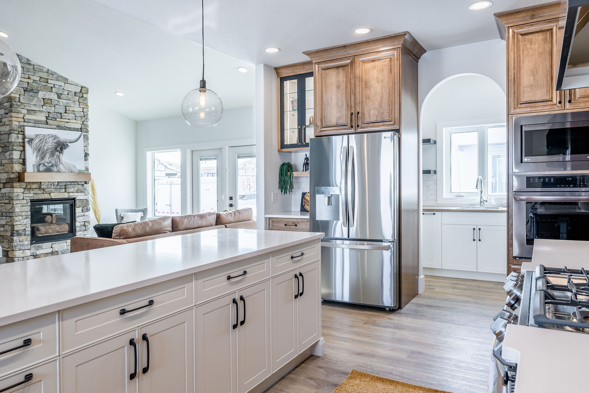 Modern kitchen with white cabinets and wooden accents, featuring stainless steel appliances and a central island. Bright, airy, and welcoming atmosphere.