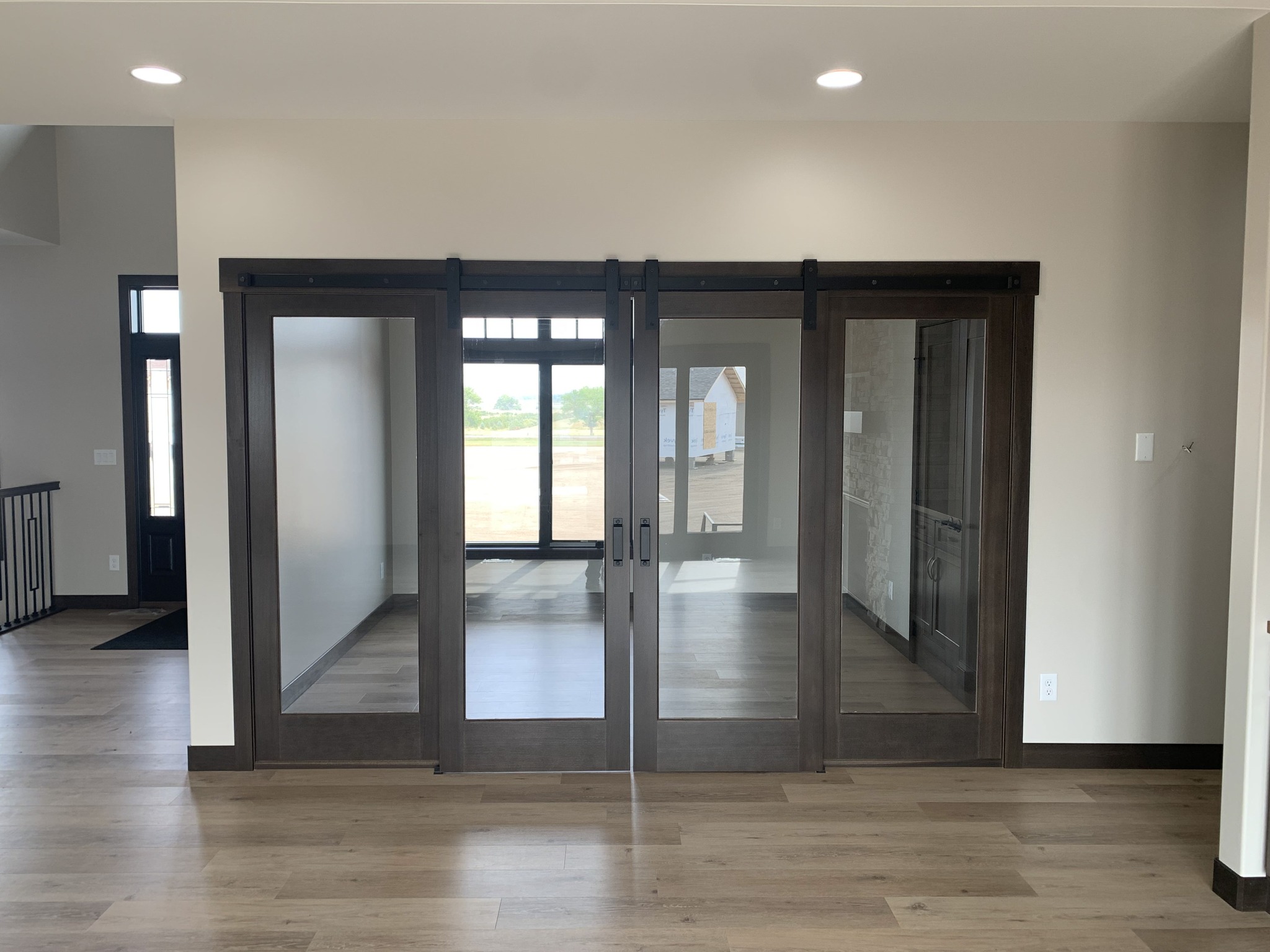 Modern room with large wooden-framed sliding glass doors leading outside. Neutral tones and natural light create an open and airy ambiance.