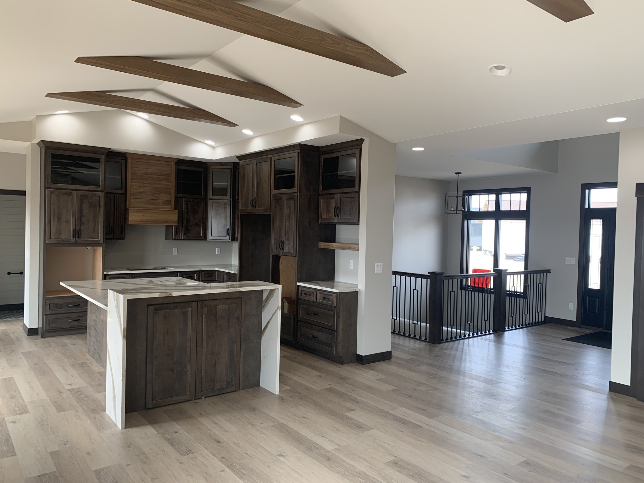 Modern kitchen with dark wood cabinets and a central island under a vaulted ceiling. Open layout with hardwood floors and natural light.