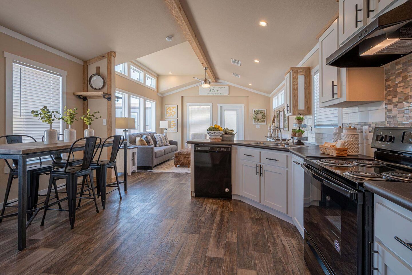 Spacious, modern kitchen and living area in neutral tones. Features sleek appliances, wooden floors, a dining table, and cozy couch, conveying warmth.