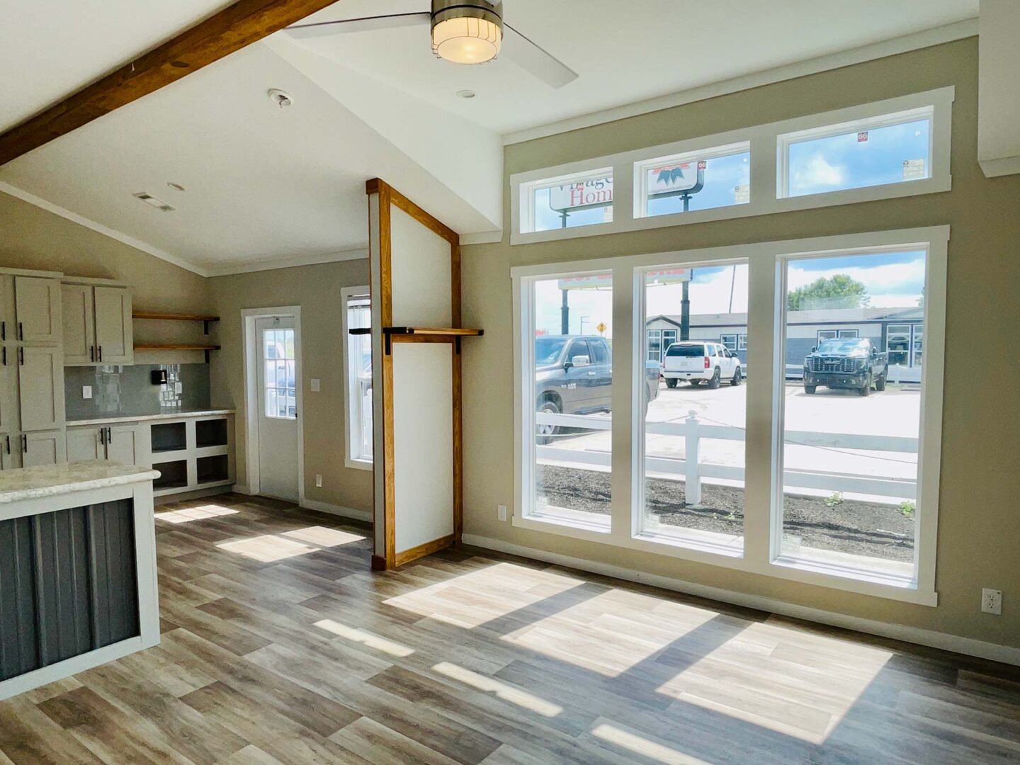 Modern, bright room with large windows, wood floors, and high ceiling. Sunlight streams in, creating a warm, inviting atmosphere.