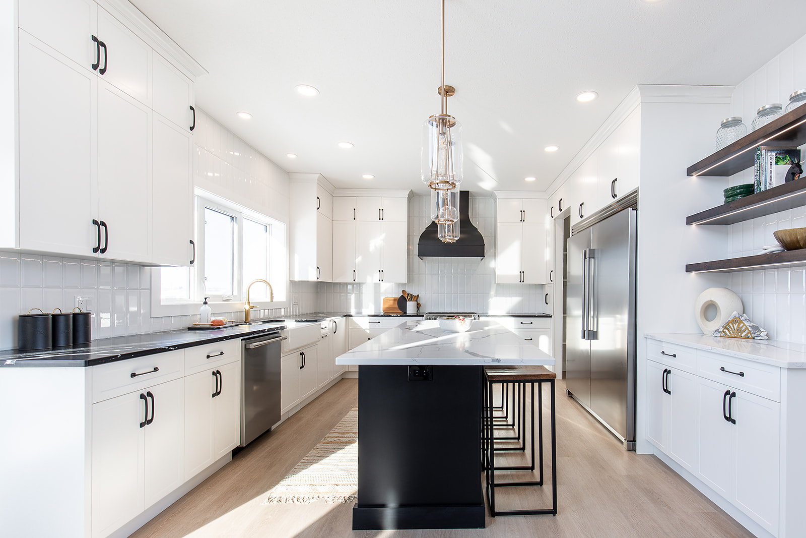 Bright, modern kitchen with white cabinets and countertops, black accents, stainless steel appliances, and wooden open shelves. Inviting and stylish.