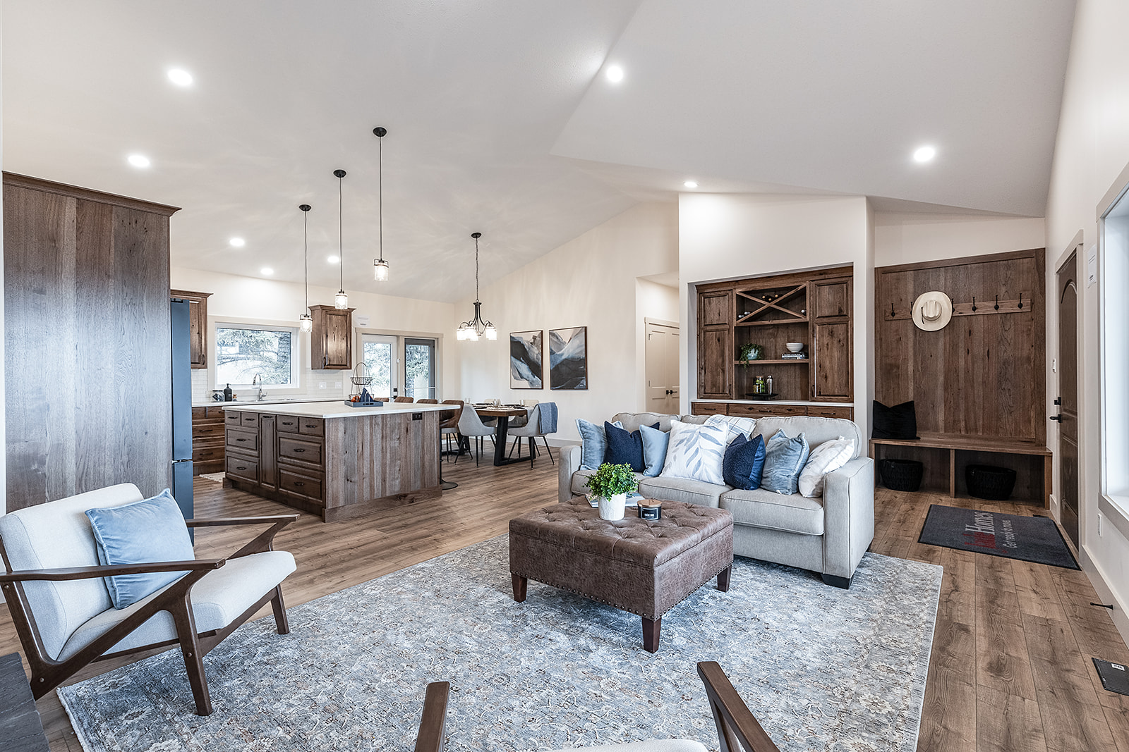 Stylish open-concept living area with cozy seating, wooden floors, and rustic kitchen. Soft lighting creates a warm, welcoming ambiance.
