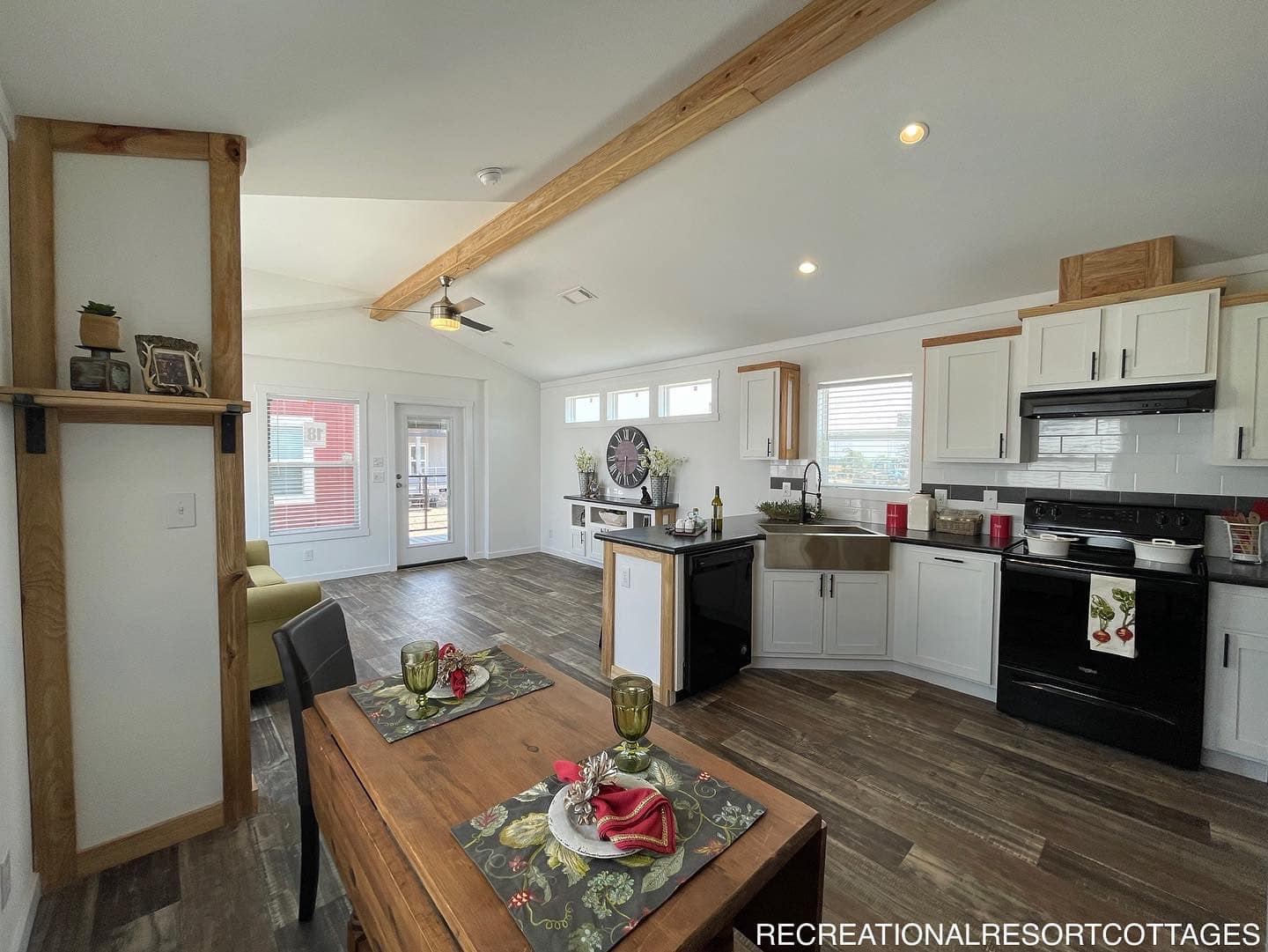 Cozy kitchen and dining area with wood accents, modern appliances, and warm lighting. A table set for two adds a welcoming, homey feel.