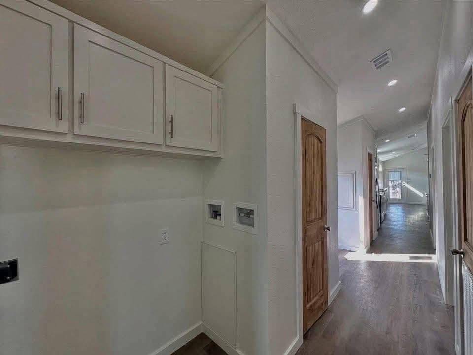 Bright hallway with wooden doors and white walls, featuring upper storage cabinets on the left and natural light streaming from windows, creating a warm, inviting ambiance.