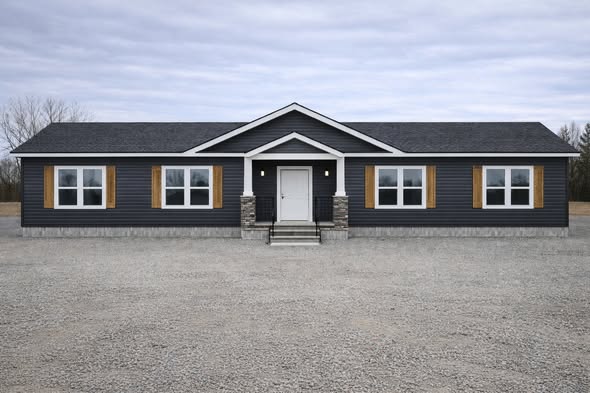 Single-story house with dark siding and white trim features a central entrance flanked by large windows. Overcast sky sets a calm, neutral tone.