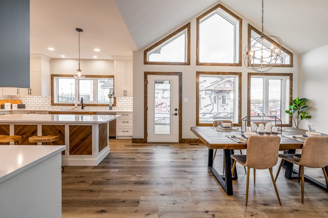 Spacious, modern kitchen and dining area with large, triangular windows, a wooden island, and rustic decor. Bright and inviting atmosphere.
