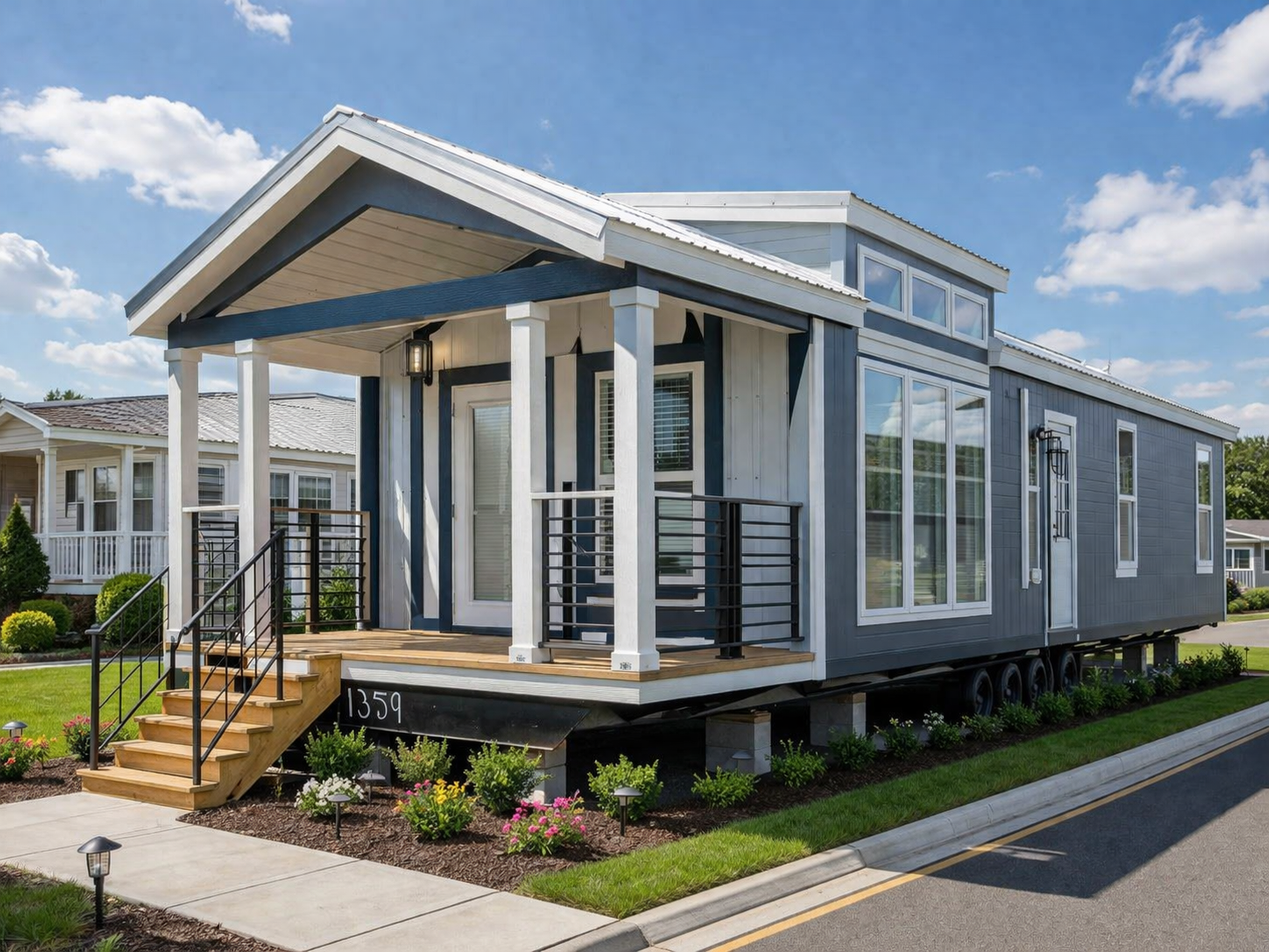 Modern tiny house on wheels with a blue and white exterior. Features a front porch, large windows, and a lush garden, under a bright sky.
